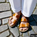 버켄스탁과 크록스의 여름 샌들 - A close-up shot of a person&rsquo;s feet wearing classic Birkenstock sandals with natural cork and leather...